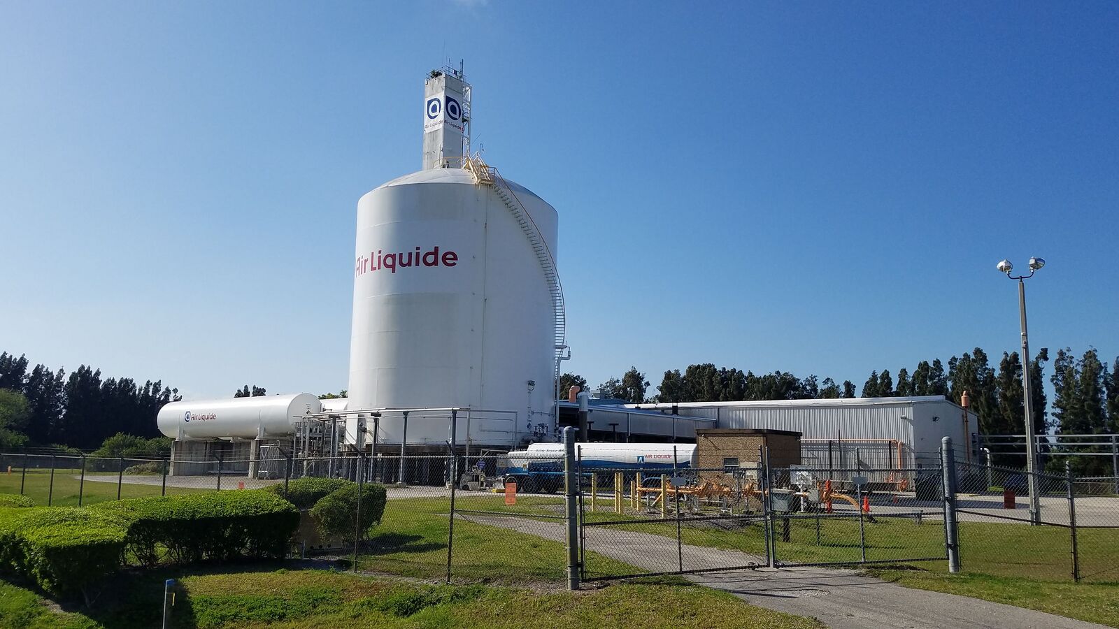 An Air Liquide air separation plant at Merritt Island, Florida, near the Cape Canaveral launch sites: a tall white cryogenic storage tank, a smaller horizontal tank and a tanker truck behind a fence. It illustrates the kind of plant proposed, not a site in Kenya.